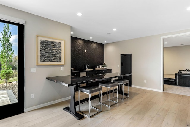 kitchen with light hardwood / wood-style floors, kitchen peninsula, and a breakfast bar area