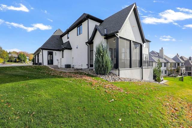 view of side of property with central AC, a sunroom, and a lawn