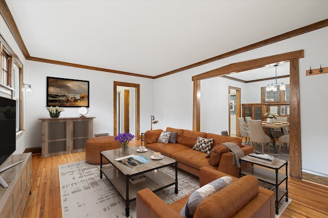 living room featuring light hardwood / wood-style flooring, ornamental molding, and a notable chandelier