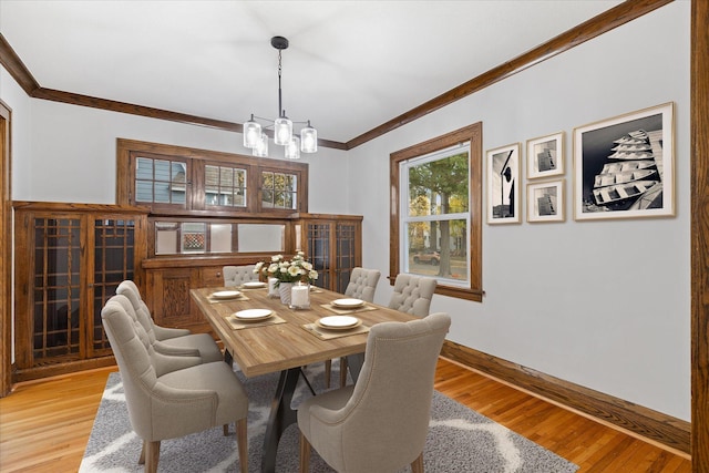 dining room with light hardwood / wood-style flooring, ornamental molding, and a notable chandelier