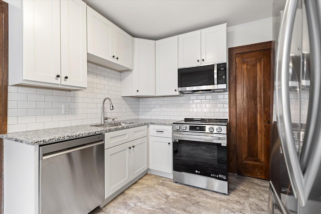 kitchen with tasteful backsplash, light stone countertops, sink, white cabinetry, and stainless steel appliances