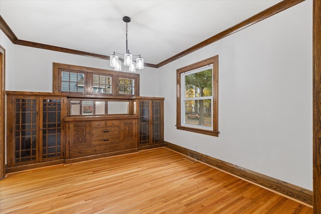 spare room with crown molding, a notable chandelier, and light wood-type flooring