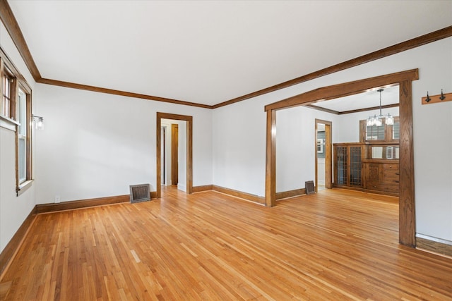 empty room featuring light hardwood / wood-style floors, a notable chandelier, and ornamental molding