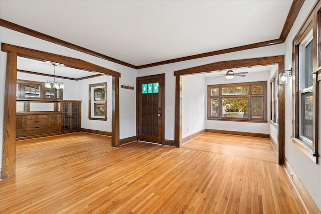 interior space with light hardwood / wood-style floors, crown molding, and ceiling fan with notable chandelier