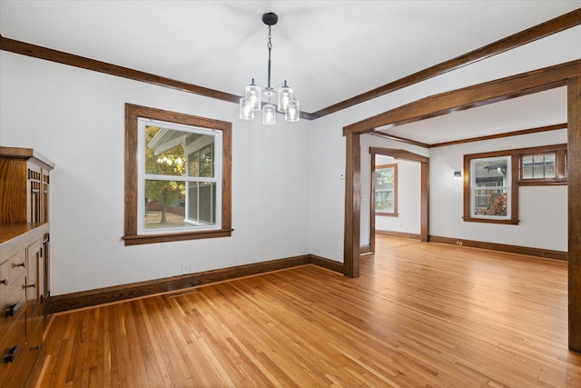 unfurnished dining area featuring ornamental molding, a chandelier, and light hardwood / wood-style flooring