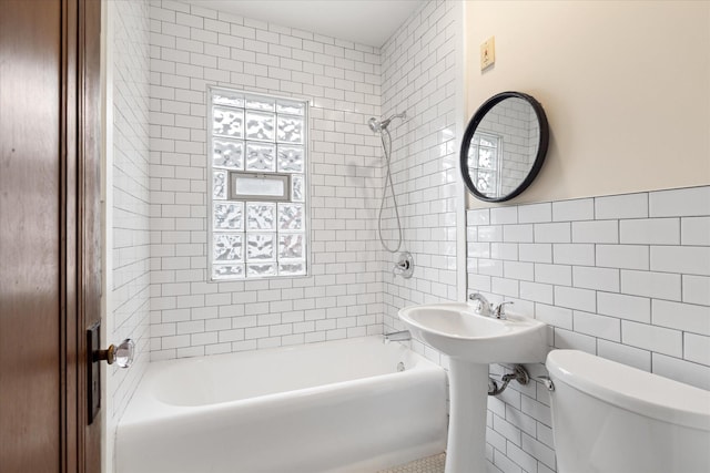 bathroom with toilet, tiled shower / bath combo, and tile walls