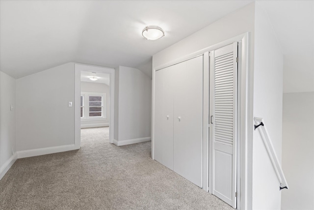 interior space with vaulted ceiling and light carpet