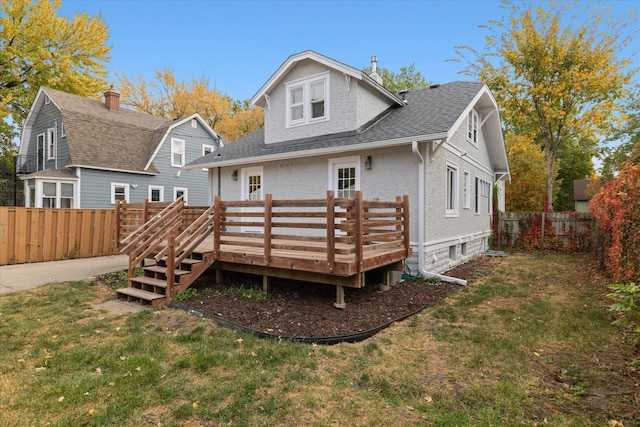 back of property featuring a wooden deck and a lawn