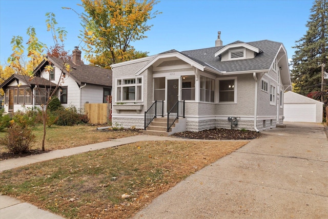 bungalow featuring a front yard, an outbuilding, and a garage