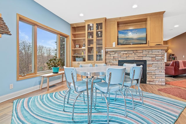 dining room featuring a stone fireplace and light wood-type flooring