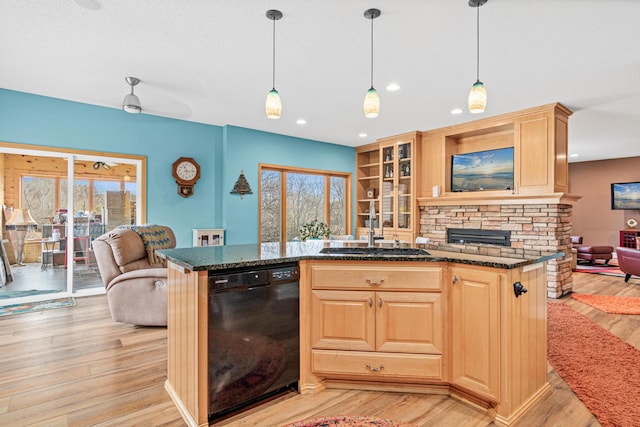 kitchen with sink, black dishwasher, plenty of natural light, dark stone counters, and light wood-type flooring