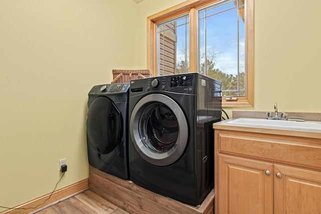 washroom featuring cabinets, independent washer and dryer, light wood-type flooring, and sink