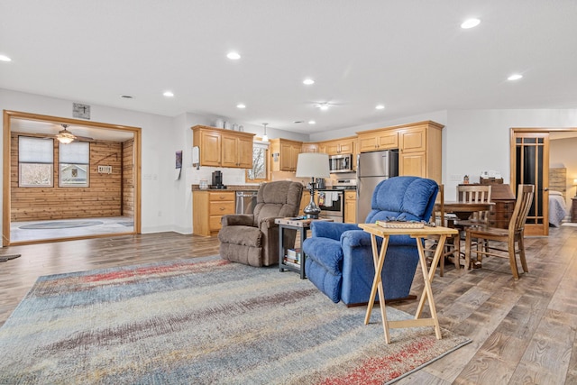 living room featuring wood walls, light hardwood / wood-style flooring, and ceiling fan