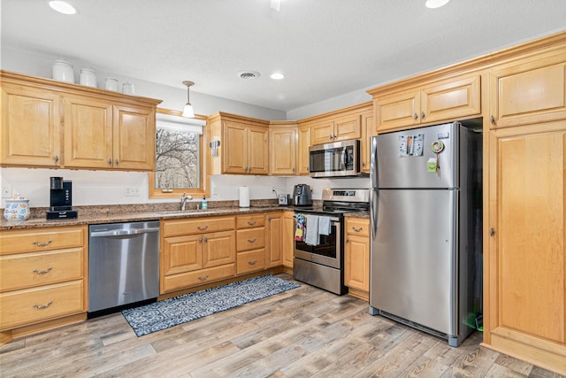 kitchen featuring stone counters, light wood-type flooring, stainless steel appliances, and sink