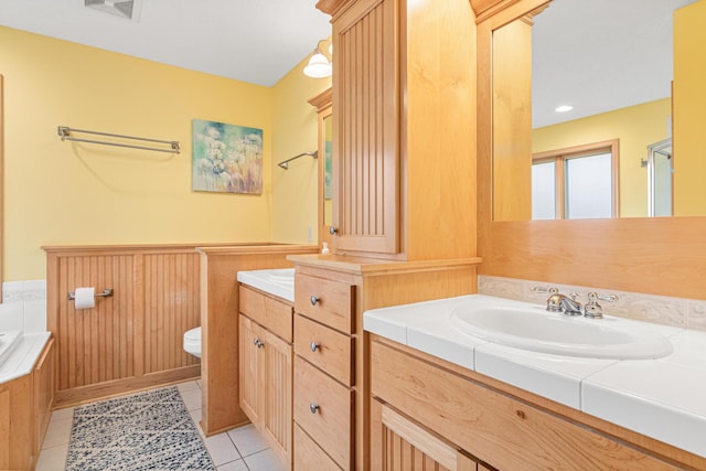 bathroom featuring tile patterned floors, a washtub, vanity, and toilet