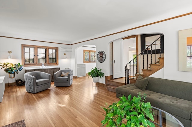 living room with ornamental molding, an AC wall unit, and wood-type flooring