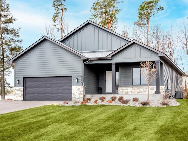 view of front of property with a front yard, central air condition unit, and a garage