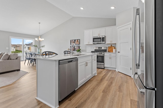 kitchen featuring light hardwood / wood-style flooring, stainless steel appliances, vaulted ceiling, and white cabinets