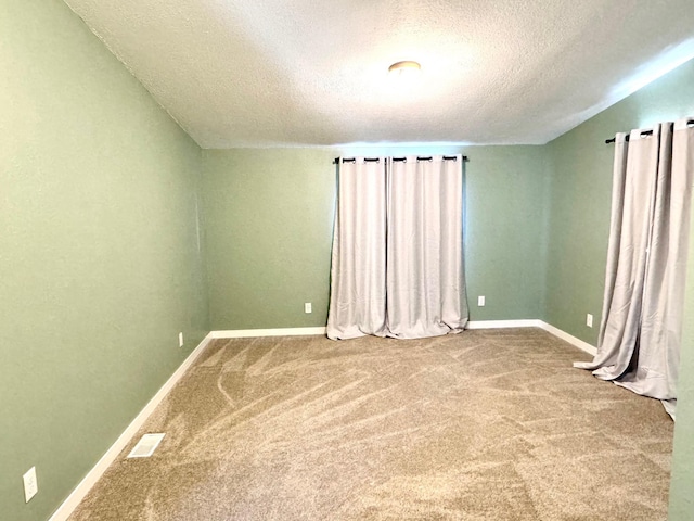 unfurnished room featuring a textured ceiling and carpet flooring