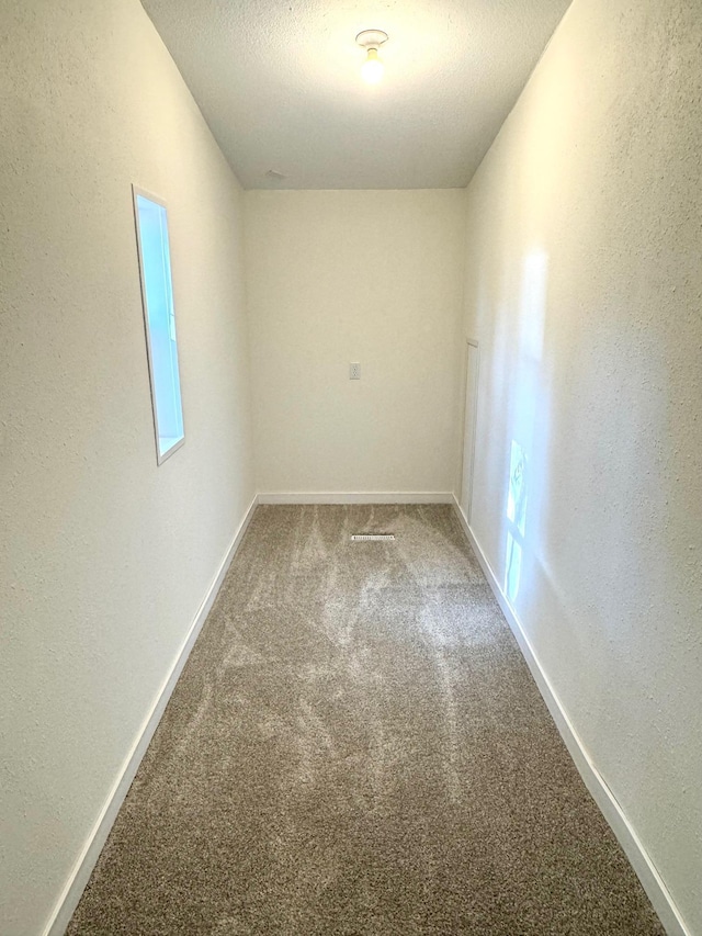 unfurnished room featuring a textured ceiling and carpet