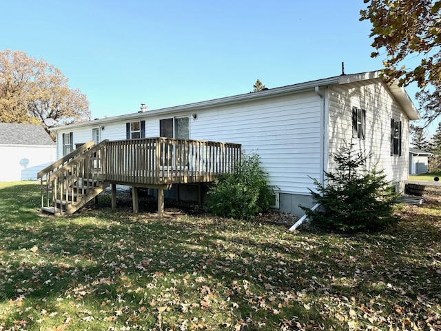 rear view of house featuring a wooden deck and a lawn