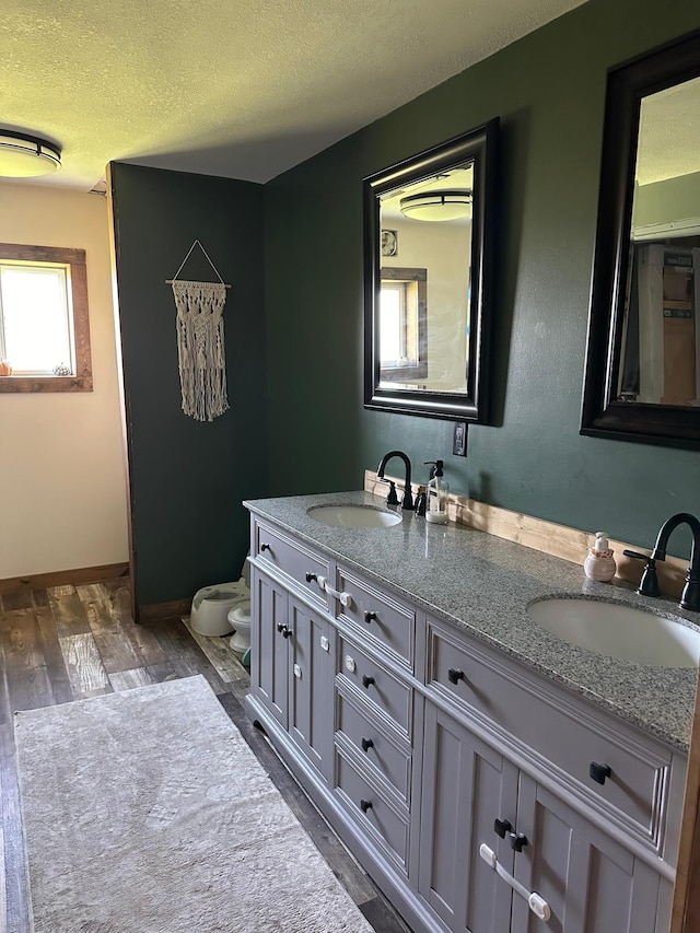 bathroom featuring vanity, toilet, hardwood / wood-style flooring, and a textured ceiling