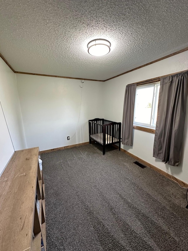 unfurnished bedroom with a nursery area, a textured ceiling, and carpet flooring