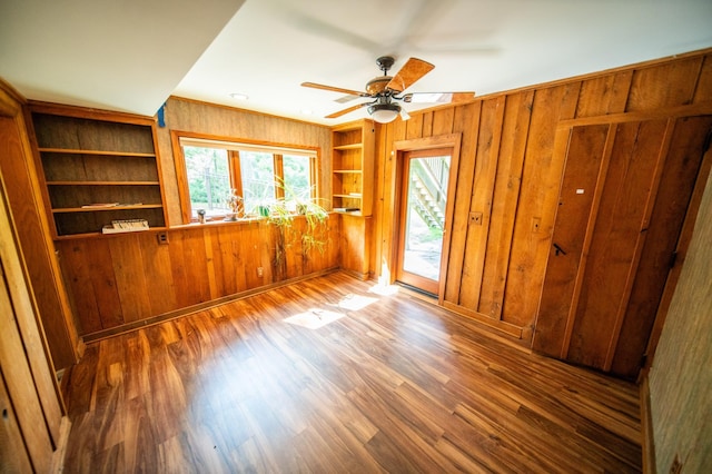 1425 20th St SW, Rochester, MN 55902 - spare room featuring wooden walls, a ceiling fan, wood finished floors, and built in shelves