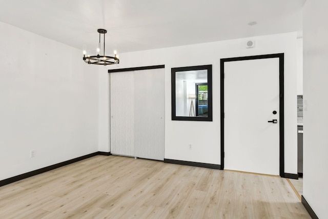 spare room featuring an inviting chandelier and light wood-type flooring