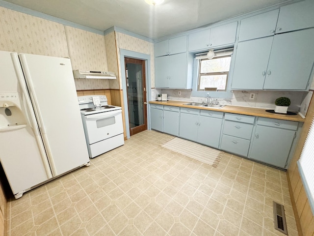 kitchen with white appliances, blue cabinetry, sink, and wooden counters