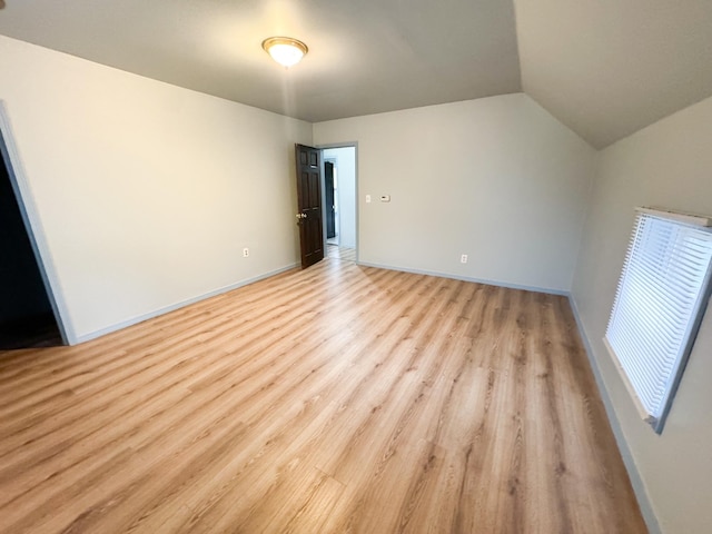 unfurnished room with lofted ceiling and light wood-type flooring