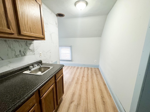 kitchen with light hardwood / wood-style floors, lofted ceiling, sink, and decorative backsplash