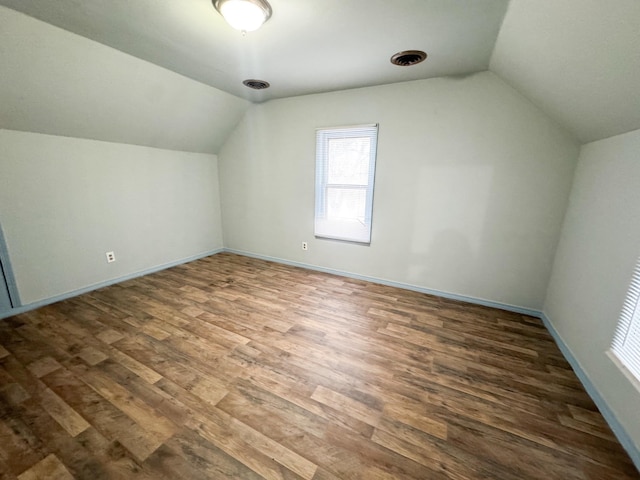 additional living space featuring vaulted ceiling and dark hardwood / wood-style flooring