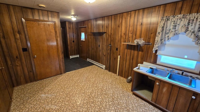 corridor with wooden walls, a baseboard heating unit, and a textured ceiling