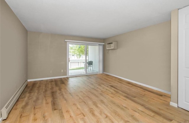 spare room featuring a baseboard heating unit, a wall mounted air conditioner, and light hardwood / wood-style floors