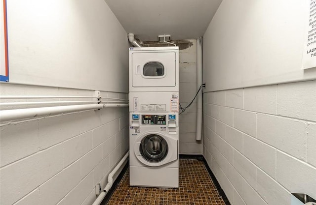 laundry room with dark tile patterned floors and stacked washer and clothes dryer