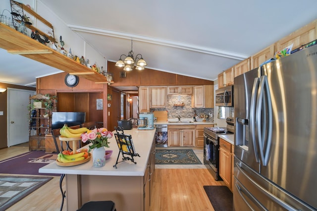 kitchen with lofted ceiling, a breakfast bar area, a sink, light countertops, and appliances with stainless steel finishes