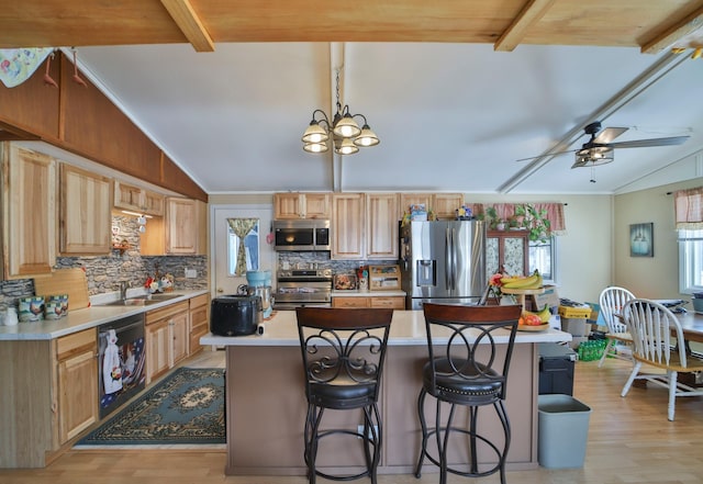 kitchen with appliances with stainless steel finishes, a breakfast bar, light countertops, and vaulted ceiling with beams