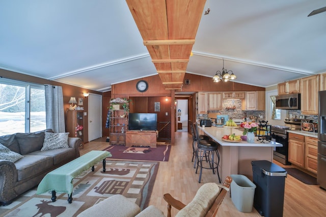 living room featuring lofted ceiling with beams, light wood finished floors, and an inviting chandelier
