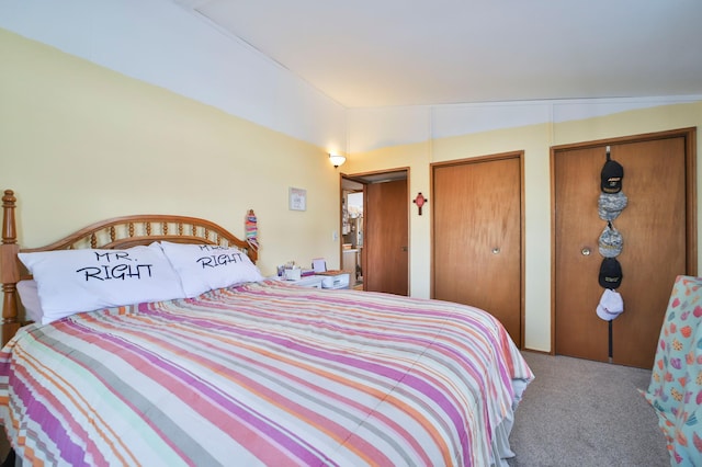 bedroom with lofted ceiling, carpet, and two closets