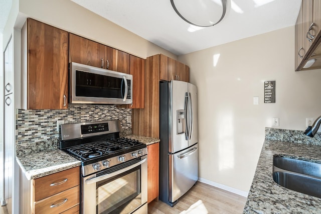 kitchen with backsplash, stainless steel appliances, sink, and stone counters