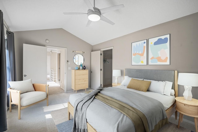 carpeted bedroom with lofted ceiling, a walk in closet, a closet, and ceiling fan