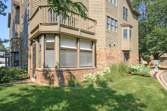 view of property exterior featuring a balcony and a lawn