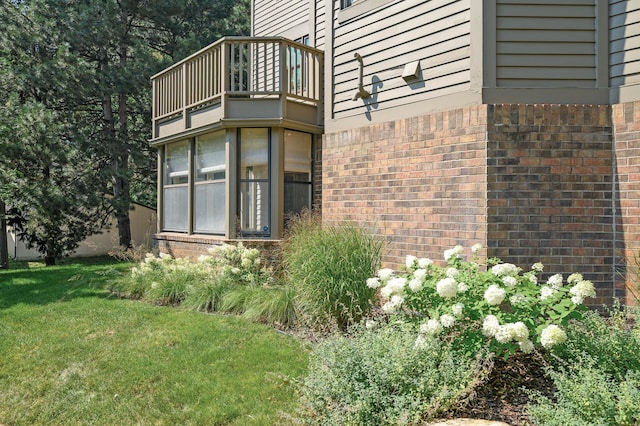 view of side of home with a balcony and a lawn