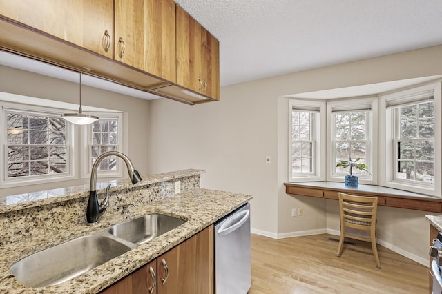 kitchen featuring pendant lighting, sink, dishwasher, built in desk, and light hardwood / wood-style floors