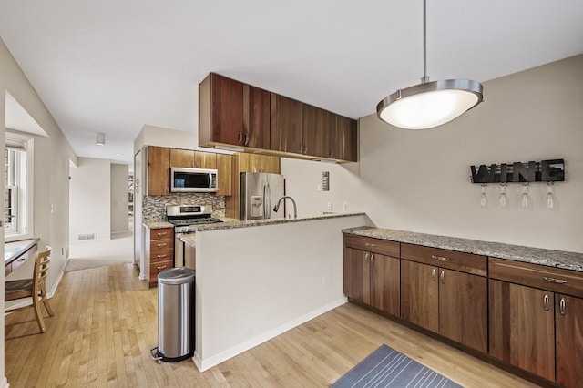 kitchen with sink, light hardwood / wood-style flooring, backsplash, stainless steel appliances, and light stone counters