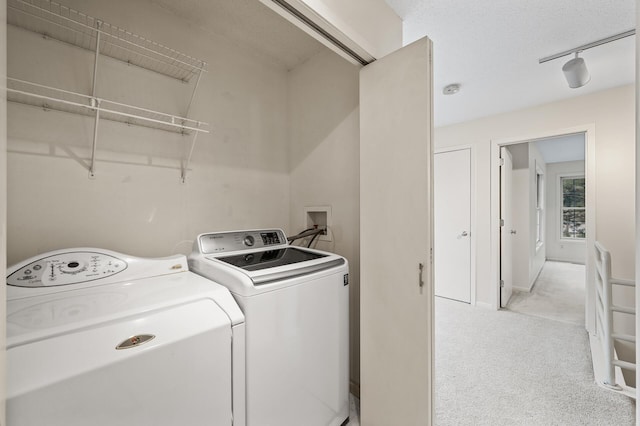 clothes washing area featuring light colored carpet, rail lighting, and washer and dryer