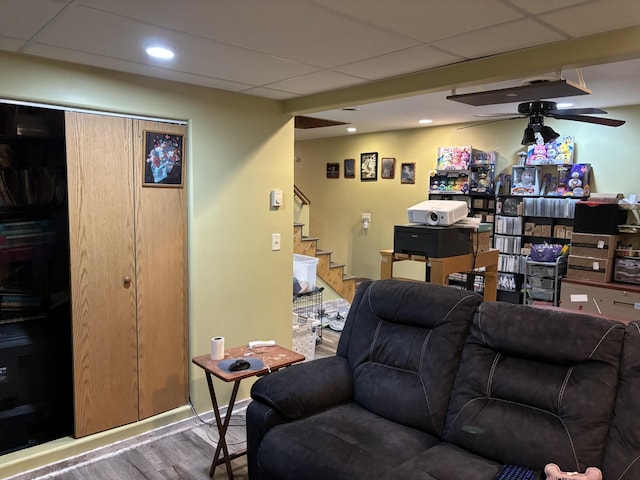 living room with a paneled ceiling, light wood-type flooring, and ceiling fan