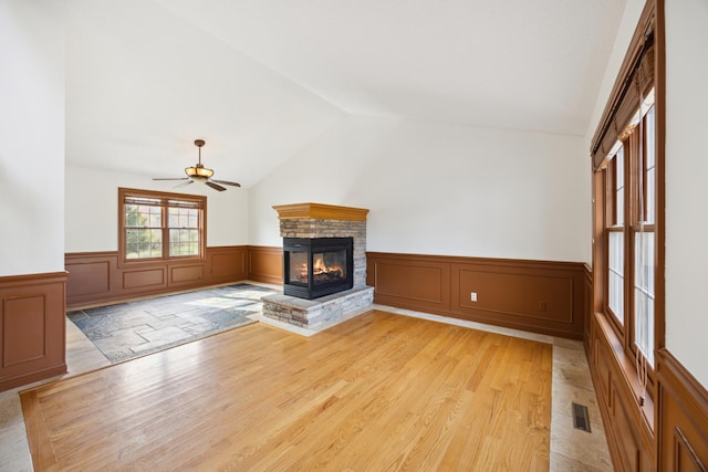 unfurnished living room featuring vaulted ceiling, a fireplace, light hardwood / wood-style floors, and ceiling fan