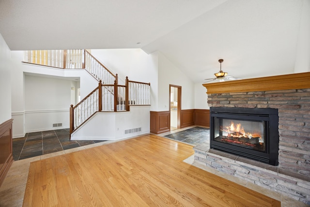 unfurnished living room featuring hardwood / wood-style flooring, high vaulted ceiling, and a fireplace